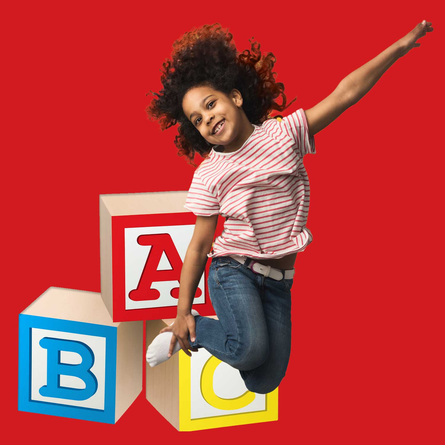 Happy young girl jumping in front of large colorful ABC blocks, wearing a red and white striped shirt, with a bright red background.