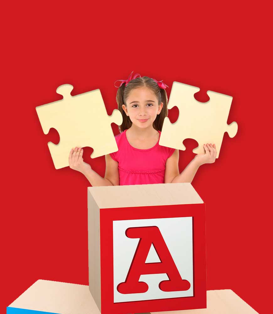 Young girl standing behind a large toy block with the letter A, holding two oversized puzzle pieces, symbolizing developmental learning and support.